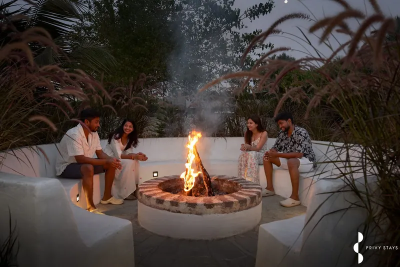 Friends talking around a bonfire in a garden at dusk