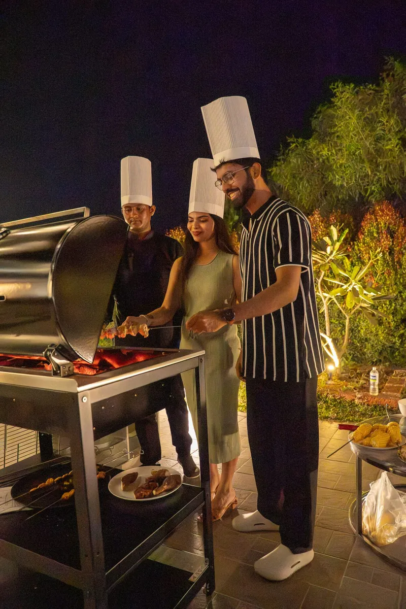 Chefs grilling at an evening barbecue with guests