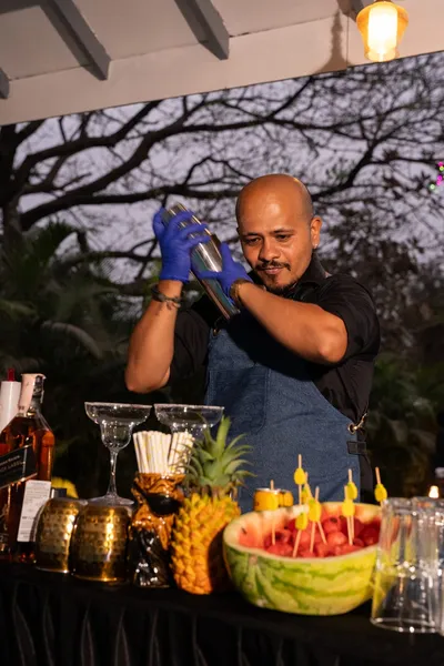 A bartender preparing drinks for guests at an evening gathering